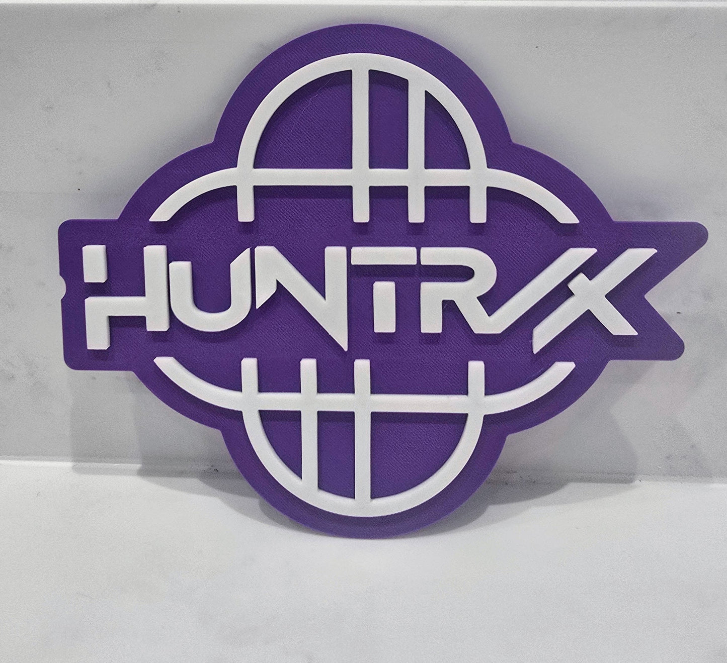 Purple and white logo with 'HUNTRX' text on a gray background