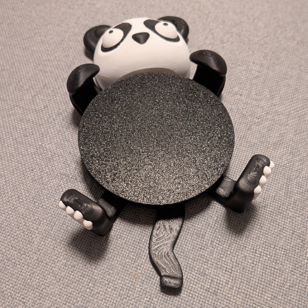 Panda-shaped object with a textured round base on a gray surface