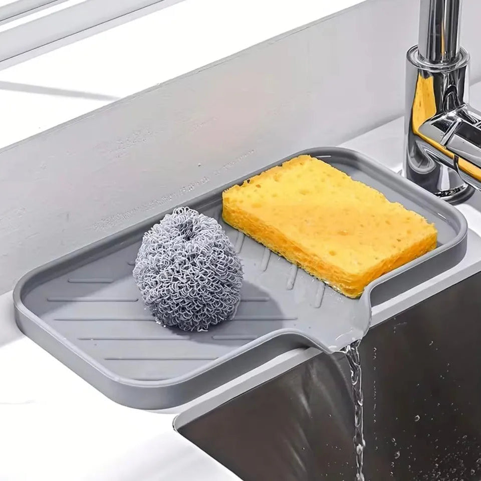 Gray sink caddy with sponge, scrubber, and soap holder on a kitchen sink.