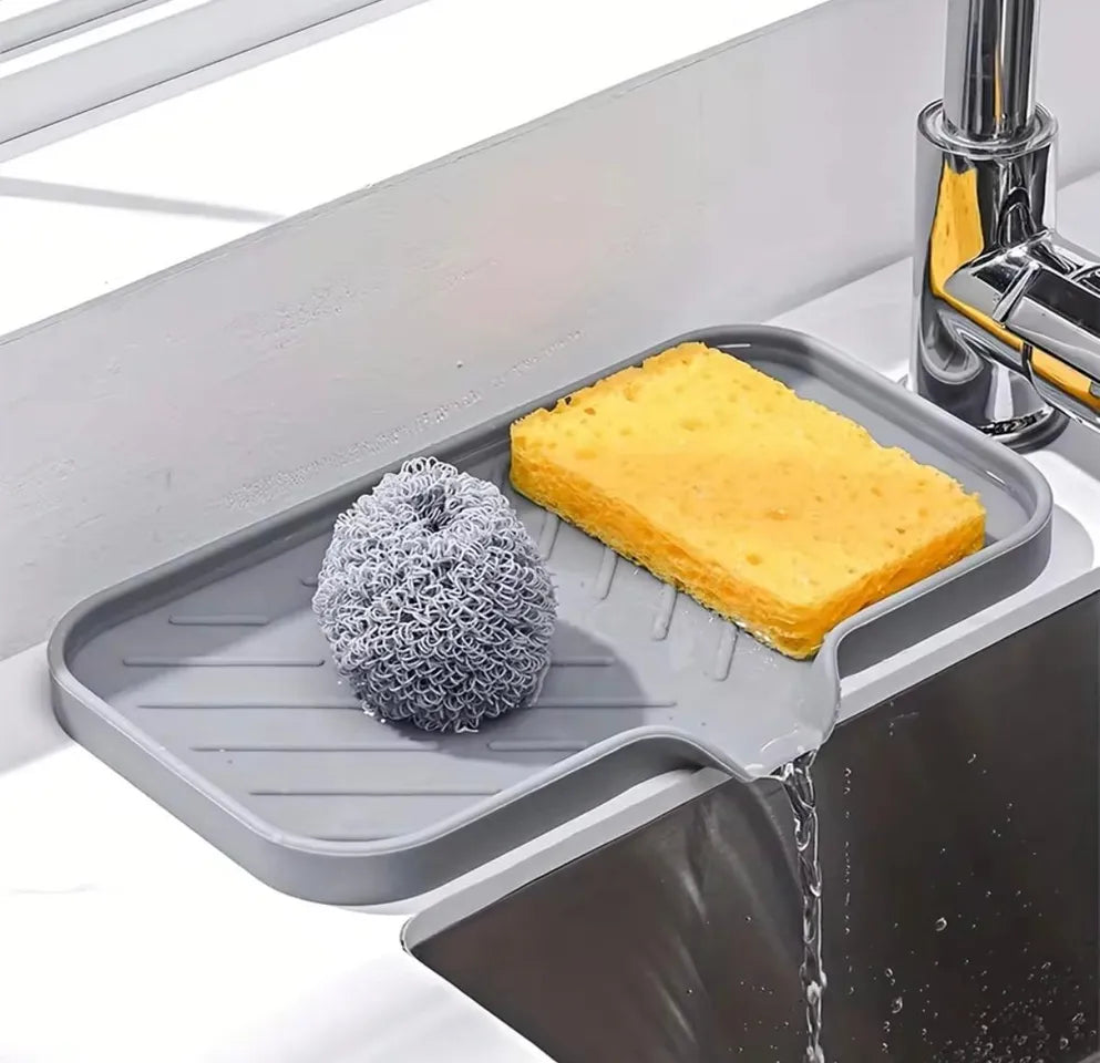Gray sink caddy with sponge, scrubber, and soap holder on a kitchen sink.